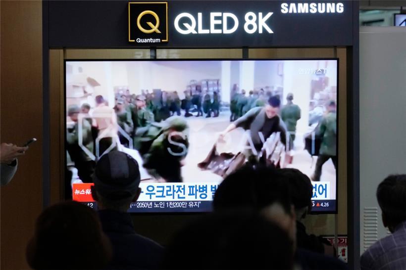 In einer Nachrichtensendung auf einem Fernsehbildschirm am Bahnhof sind Soldaten zu sehen, die vermutlich aus Nordkorea stammen und bereitstehen, um Nachschub aus Russland zu erhalten
