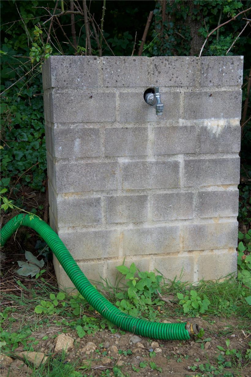 In vielen Gärten sind Plastikschläuche verlegt. Alle führen unter den Hauptweg. ...