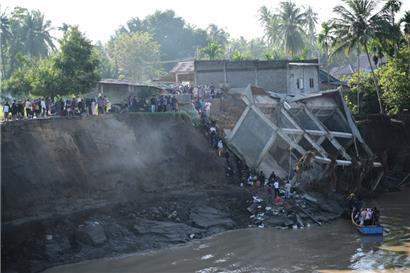 Indonesien, Bireun: Menschen gehen die Böschung eines Flusses hinunter, um ein Boot zu nehmen, nachdem eine Brücke in der Nähe während einer Überschwemmung eingestürzt ist
