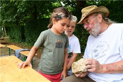 Interesse wecken: Geduldig erklärt Paläontologe Guy Kronz, welche Fossilien sich auf dem Stein befinden. Lyel und Jang staunen – besonders darüber, dass diese Versteinerungen um die 130 Millionen Jahre alt sind.
