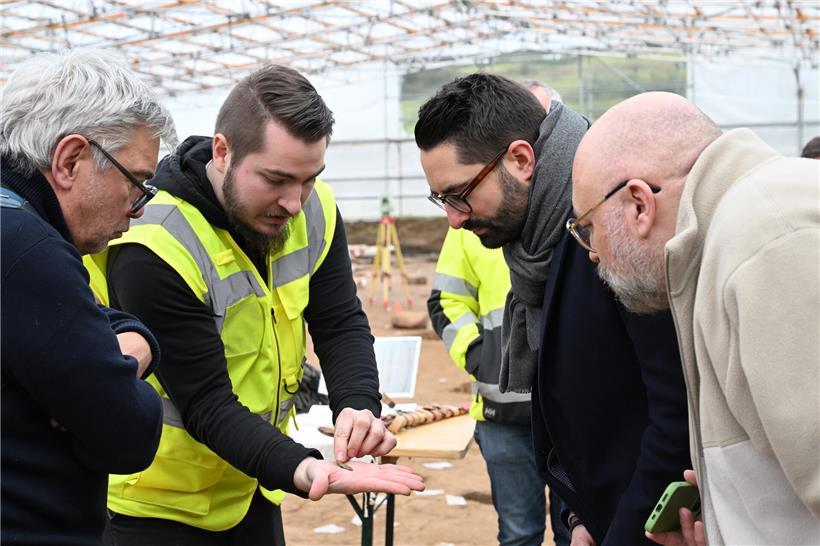 Besucher betrachten eine seltene antike Münze aus Gold bei einer Ausstellung historischer Fundstücke