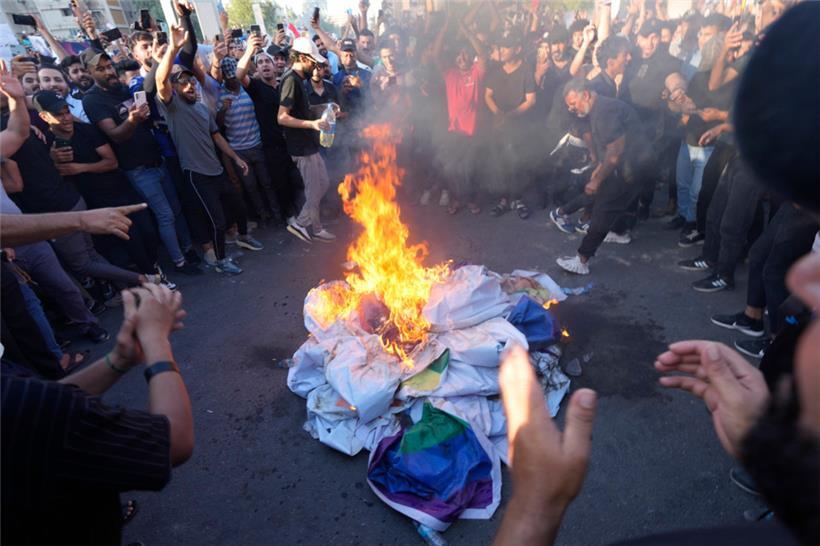 Irak, Bagdad: Anhänger des schiitischen Geistlichen Moqtada Sadr verbrennen eine Regenbogenfahne während einer Demonstration vor der schwedischen Botschaft. Nach der Verbrennung eines Korans in Schweden haben im Irak Hunderte Menschen demonstriert. 
