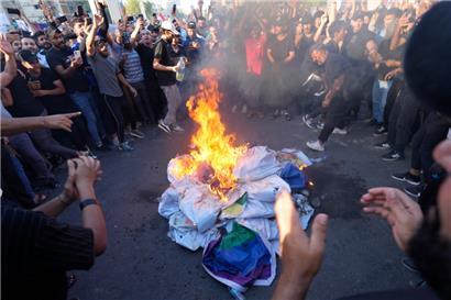 Irak, Bagdad: Anhänger des schiitischen Geistlichen Moqtada Sadr verbrennen eine Regenbogenfahne während einer Demonstration vor der schwedischen Botschaft. Nach der Verbrennung eines Korans in Schweden haben im Irak Hunderte Menschen demonstriert. 
