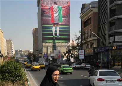 Iran, Teheran: Ein staatlich gesponsertes Plakat, das einen Fußballspieler mit der Nationalflagge beim Einlaufen in ein Stadion zeigt, hängt an einem Gebäude. Die Fußball-Nationalspieler von Iran nehmen an der Fußball-WM 2022 in Katar teil. Seit dem Tod der iranischen Kurdin Amini Mitte September gibt es anhaltende landesweite systemkritische Proteste im Iran.
