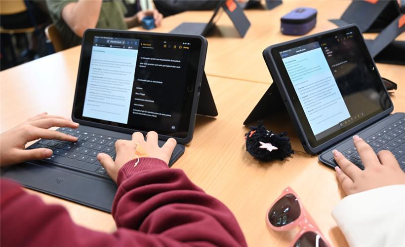 Ist digital besser? Zwei Mädchen arbeiten mit einem KI-Chatbot.
