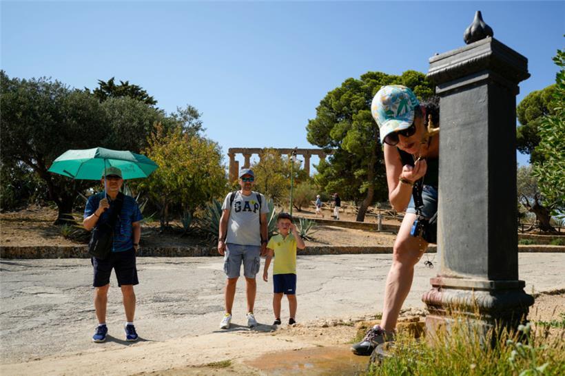 Italien, Agrigento: Besucher erfrischen sich an einem Trinkbrunnen im archäologischen Park Tal der Tempel
