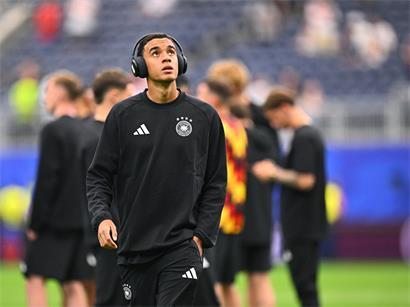 Jamal Musiala geht vor dem Spiel mit Kopfhörern über den Platz – warum das zum Problem wurde