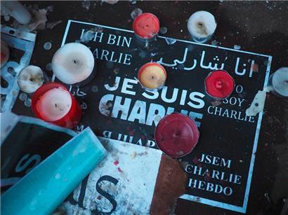 „Je suis Charlie“ (Ich bin Charlie), geschrieben auf einem Plakat, umgeben von Gedenktafeln für die Opfer des Terroranschlags auf das Hauptquartier der französischen Satirezeitschrift Charlie Hebdo
