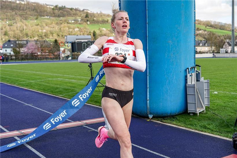 Jenny Gloden gewinnt den Zehn-Kilometer-Lauf der Damen, siegreich beim Wettkampf mit Laufmedaille und Sportkleidung