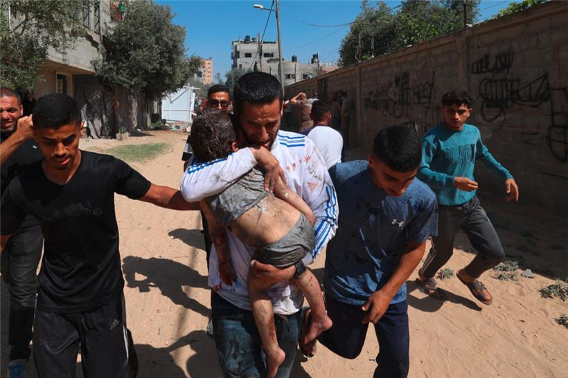 Junge Männer laufen mit einem durch israelischen Beschuss verletzten Kind zu einer medizinischen Einrichtung
