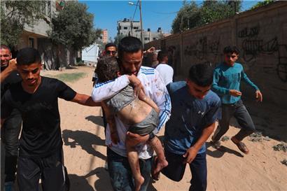 Junge Männer laufen mit einem durch israelischen Beschuss verletzten Kind zu einer medizinischen Einrichtung
