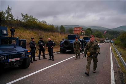KFOR-Soldaten marschieren am serbisch-kosovarischen Grenzübergang Jarinje an Mitgliedern einer Sondereinheit der Polizei Kosovos vorbei
