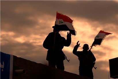 Kämpfer von Milizen im Irak, die vom Iran unterstützt werden, bekannt als die „Popular Mobilization Forces“, schwenken irakische Flaggen.
