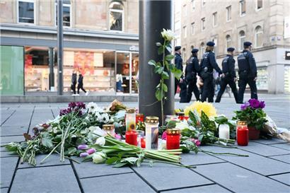 Kerzen und Blumen liegen in der Nähe des Paradeplatzes an einer Straßenbahnhaltestelle in Mannheim
