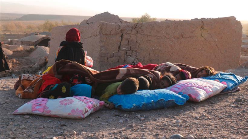 Kinder in der afghanischen Ortschaft Sarbuland schlafen mit ihren Decken neben zerstörten Häusern
