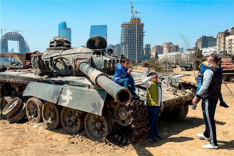 Kinder posieren auf zerschossenem Kriegsgerät
