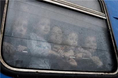 Kinder schauen an der Bahnstation in Kramatorsk aus dem Fenster eines Zuges, der auf die Abfahrt in die Westukraine wartet
