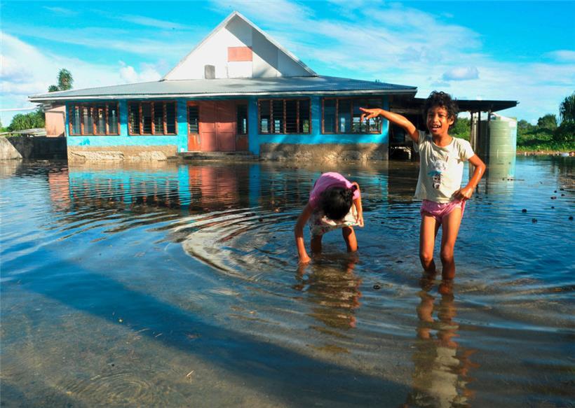 Kinder spielen am 30. Januar 2014 auf einem vom Meerwasser überfluteten Platz in Funafuti, der Hauptstadt von Tuvalu
