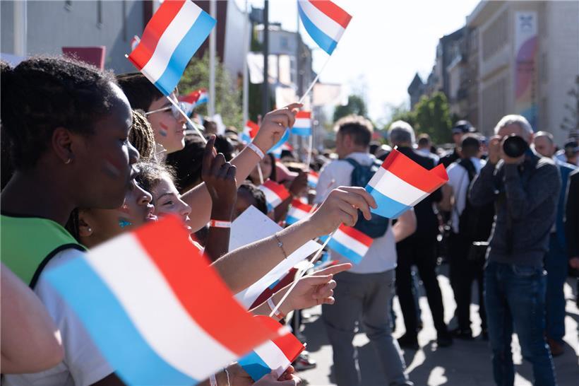 Kinder winken fröhlich mit rot-weiß-blauen Fahnen bei einer patriotischen Feier im Freien