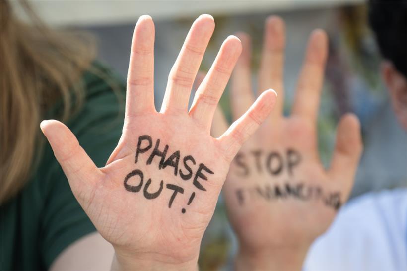 Klimaaktivisten haben sich bei einem Protest in Dubai „Phase Out!“ und „Stop Financing“ auf die Hände geschrieben

