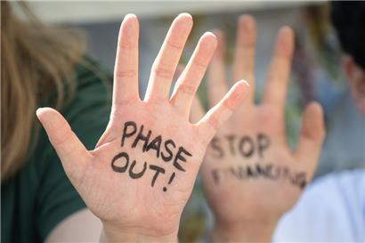 Klimaaktivisten haben sich bei einem Protest in Dubai „Phase Out!“ und „Stop Financing“ auf die Hände geschrieben
