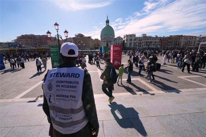 Kontrolleure überprüfen die QR-Codes von Touristen vor dem Hauptbahnhof in Venedig
