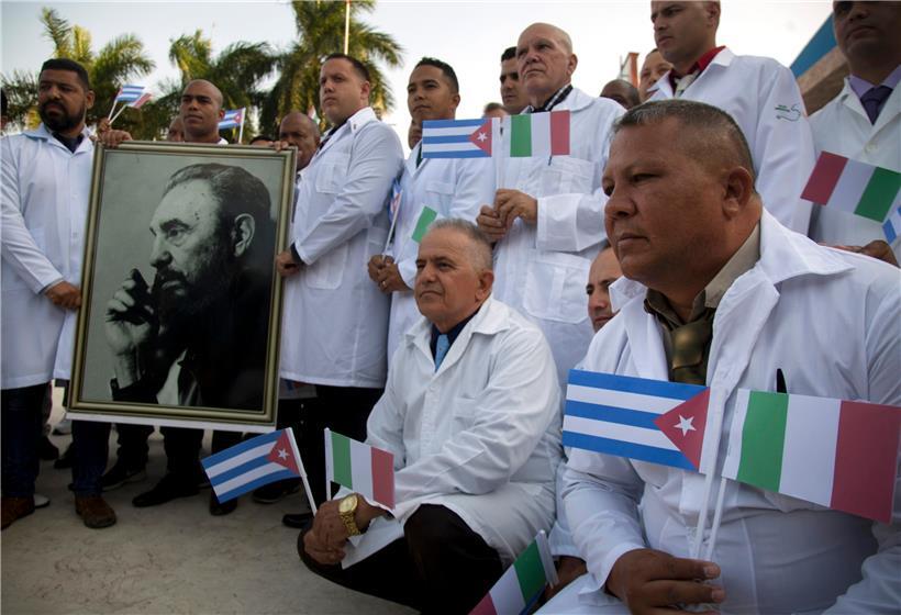 Kubanische Ärzte und Fachleute aus dem medizinischen Bereich lassen sich mit einem Foto von Fidel Castro, sowie kubanischen und italienischen Landesflaggen vor ihrer Reise nach Italien fotografieren. 
