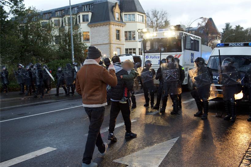 Kurz nach dem Einsatz des Wasserwerfers am 11. Dezember 2021 trägt ein Mann ein sichtlich verstörtes Kind in Richtung der Polizeisperre
