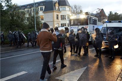 Kurz nach dem Einsatz des Wasserwerfers am 11. Dezember 2021 trägt ein Mann ein sichtlich verstörtes Kind in Richtung der Polizeisperre
