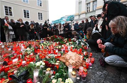 Leute stellen Kerzen auf und legen Blumengebinde vor der Karls-Universität nieder zum Gedenken an die Opfer des Amoklaufs am Donnerstag
