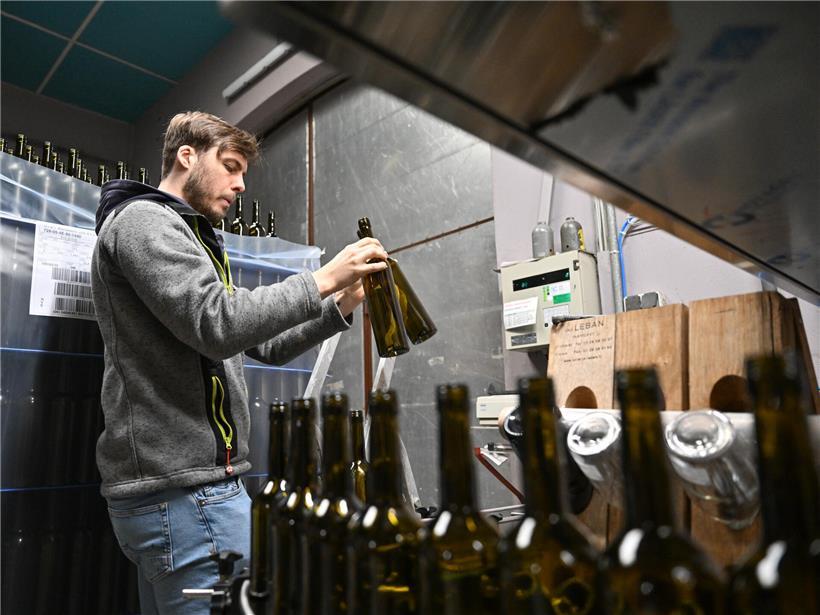 Lokalchef Cédric Feyereisen stellt leere Flaschen auf das Fließband in der Produktionshalle