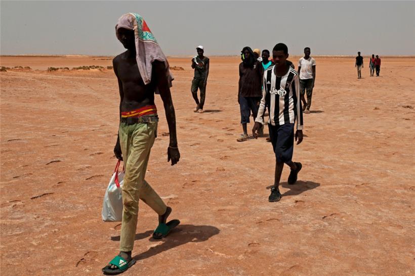 Männer kommen nach einem Marsch durch die Wüste an der libysch-tunesischen Grenze in der Nähe von Al-Assah an
