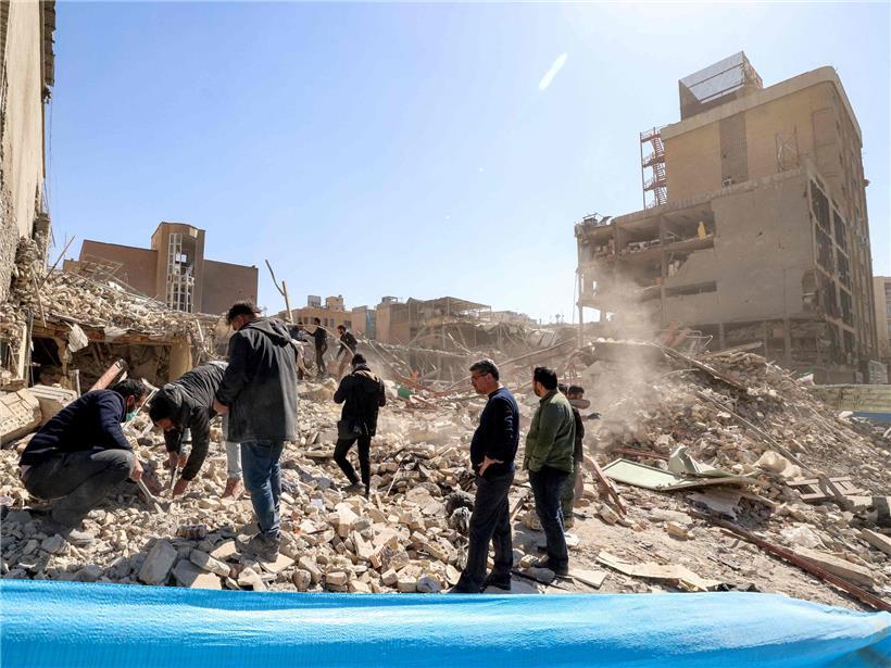 Männer stehen auf Trümmern eines zerstörten Gebäudes in Teheran nach einem Erdbeben