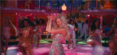 Margot Robbie als Barbie steht im Zentrum einer Party in Barbieland in einer Szene der Films „Barbie“ 
