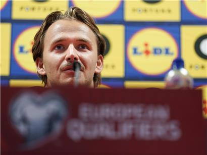 Porträt von Mathias Olesen, professioneller Fußballspieler in Sportkleidung, lächelnd vor neutralem Hintergrund