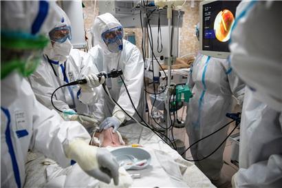 Medizinische Mitarbeiter in Schutzkleidung führen eine endotracheale Intubation bei einem Covid-19-Patienten durch. 
