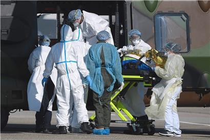 Medizinisches Personal heben einen Patienten in einen militärischen NH90 Transporthubschrauber. 
