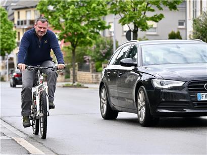 Radfahrer und Autos teilen sich eine Straße, veranschaulicht Herausforderungen der Mobilitätswende im Straßenverkehr