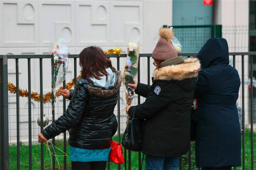Menschen befestigen Blumen am Zaun vor einer Erdgeschosswohnung: Eine Mutter und ihre vier Kinder sind in Meaux östlich von Paris tot in ihrer Wohnung aufgefunden worden
