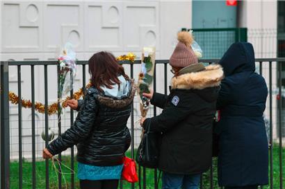 Menschen befestigen Blumen am Zaun vor einer Erdgeschosswohnung: Eine Mutter und ihre vier Kinder sind in Meaux östlich von Paris tot in ihrer Wohnung aufgefunden worden
