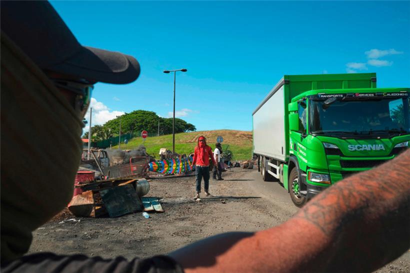 Menschen bemannen eine Straßensperre mit Kanak-Fahnen
