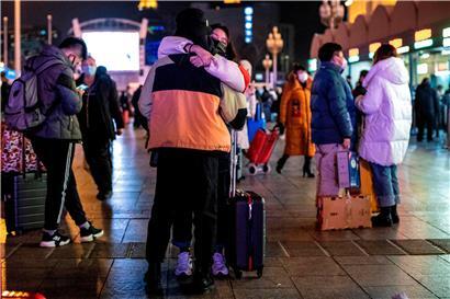 Menschen, die Schutzmasken tragen, kommen im Pekinger Bahnhof an
