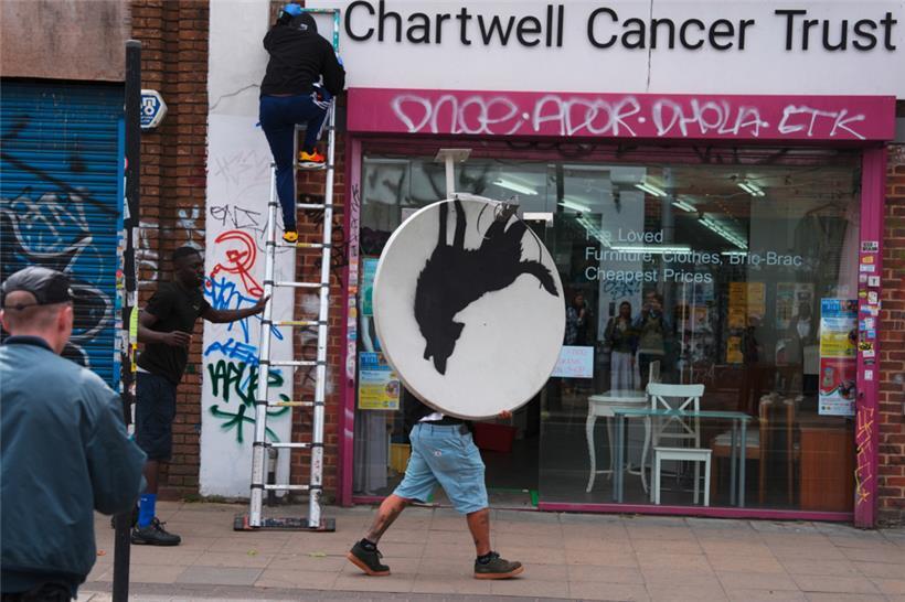 Menschen entfernen ein neues Kunstwerk von Banksy, das einen heulenden Wolf auf ...