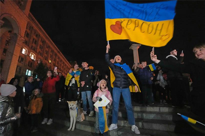 Menschen feiern und schwenken eine ukrainische Fahne, nachdem sie erfahren haben, dass ukrainische Truppen in die südliche Stadt Cherson, die Hauptstadt der Ende September von Russland annektierten Region Cherson, eingedrungen sind 
