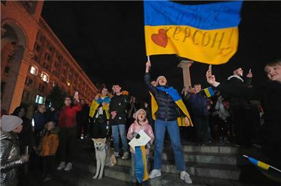 Menschen feiern und schwenken eine ukrainische Fahne, nachdem sie erfahren haben, dass ukrainische Truppen in die südliche Stadt Cherson, die Hauptstadt der Ende September von Russland annektierten Region Cherson, eingedrungen sind 
