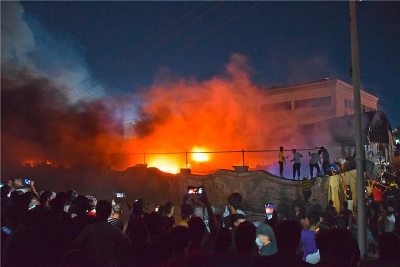 Menschen fotografieren und filmen das Feuer im Krankenhaus – wegen einer fehlerhaften Verkabelung soll ein Funken auf Sauerstoffbehälter übergesprungen sein, die dann explodierten
