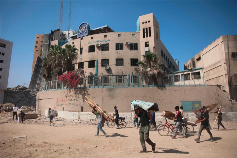 Menschen gehen an Trümmern und beschädigten Gebäuden vorbei, nachdem sich die israelischen Truppen aus dem Bürogebäude des UN-Hilfswerks für Palästinaflüchtlinge (UNRWA) im westlichen Stadtteil Al-Sinaa von Gaza-Stadt zurückgezogen haben
