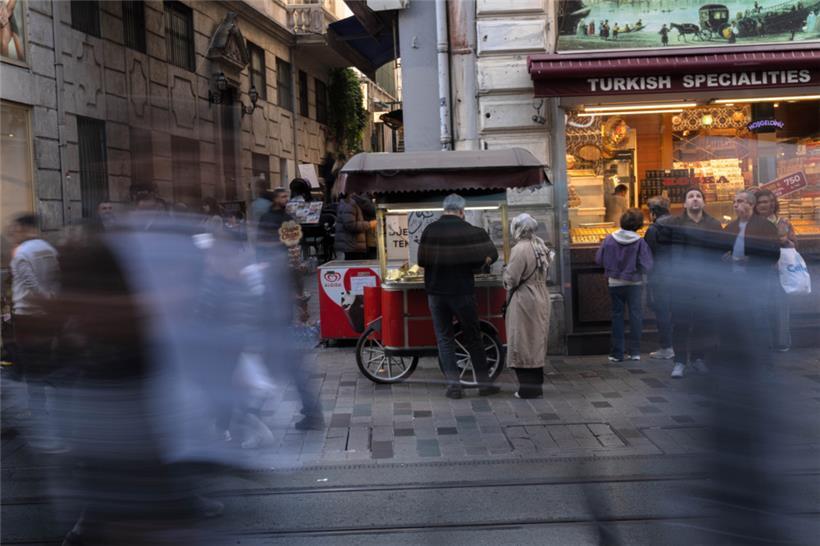Menschen gehen an einem Imbissstand auf der Istiklal-Straße vorbei, einer belebten Fußgängerzone, die für ihr Street Food und ihren historischen Charme bekannt ist
