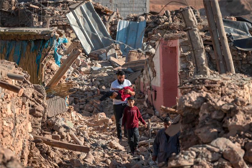 Menschen gehen an zerstörten Häusern im Bergdorf Tafeghaghte vorbei