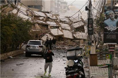 Menschen gehen in Beirut entlang einer Straße, die durch die Trümmer eines bei einem israelischen Luftangriff zerstörten Gebäudes blockiert ist